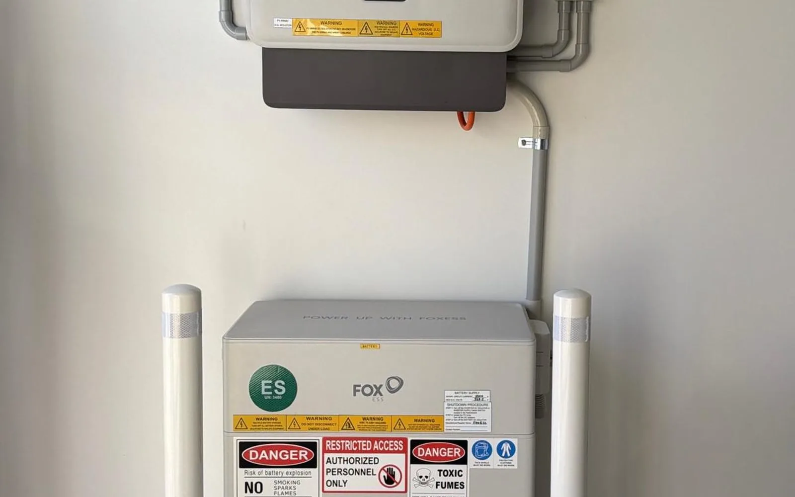 Battery and inverter neatly installed and labelled in a garage